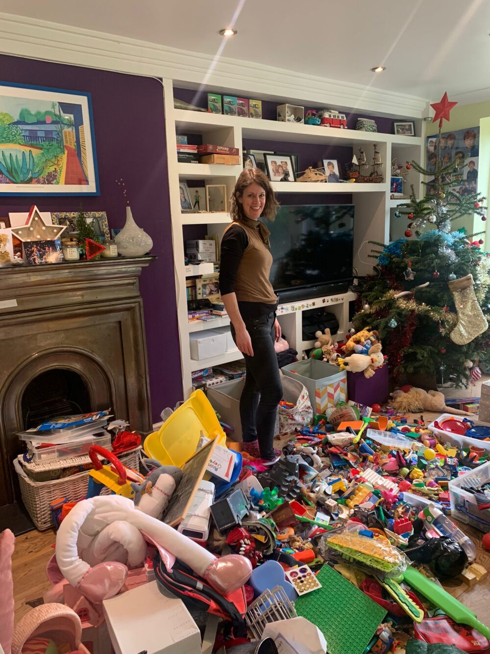 A woman standing in a living room, surrounded by lots of toys