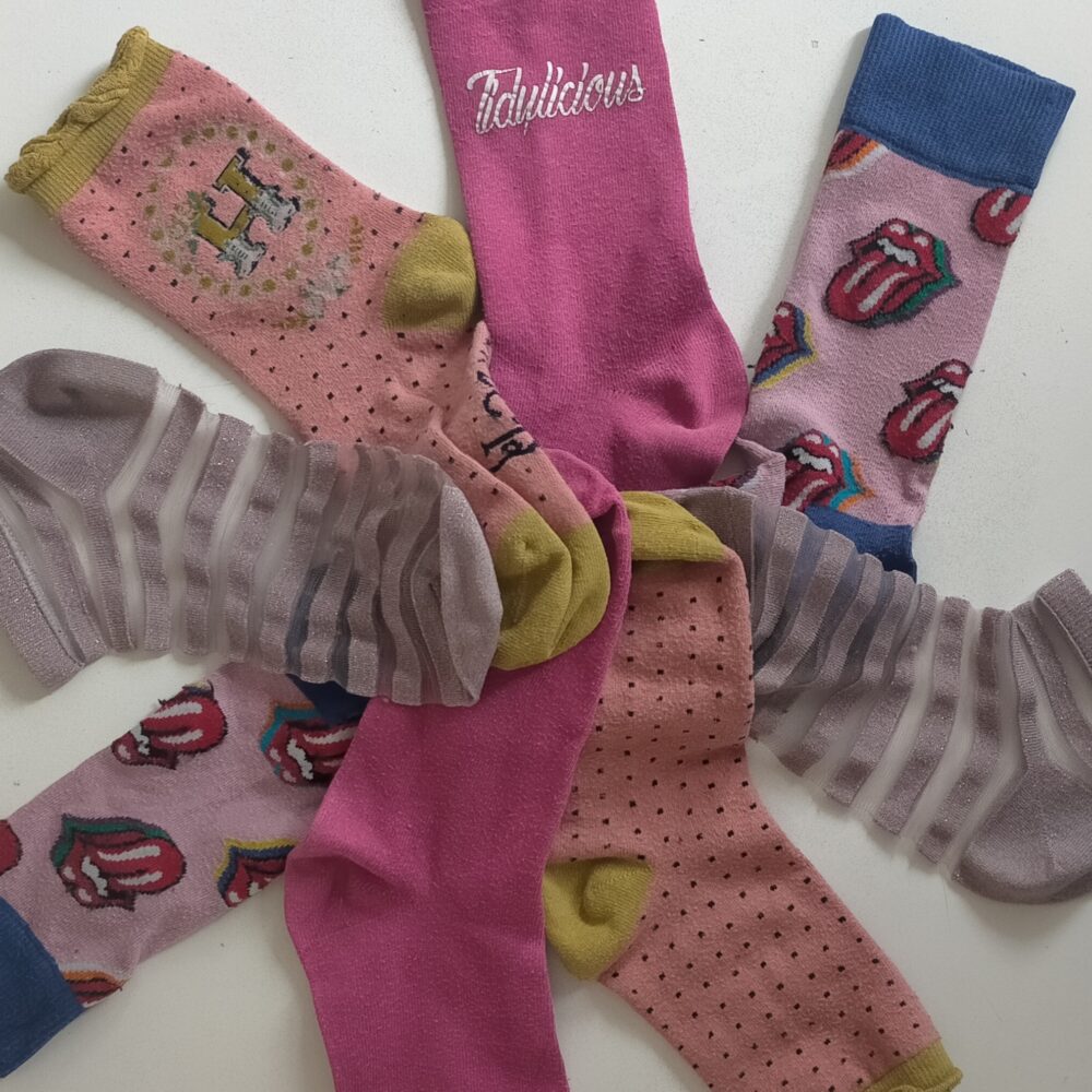 a variety of socks, in different hues of pink, photographed in a circle.