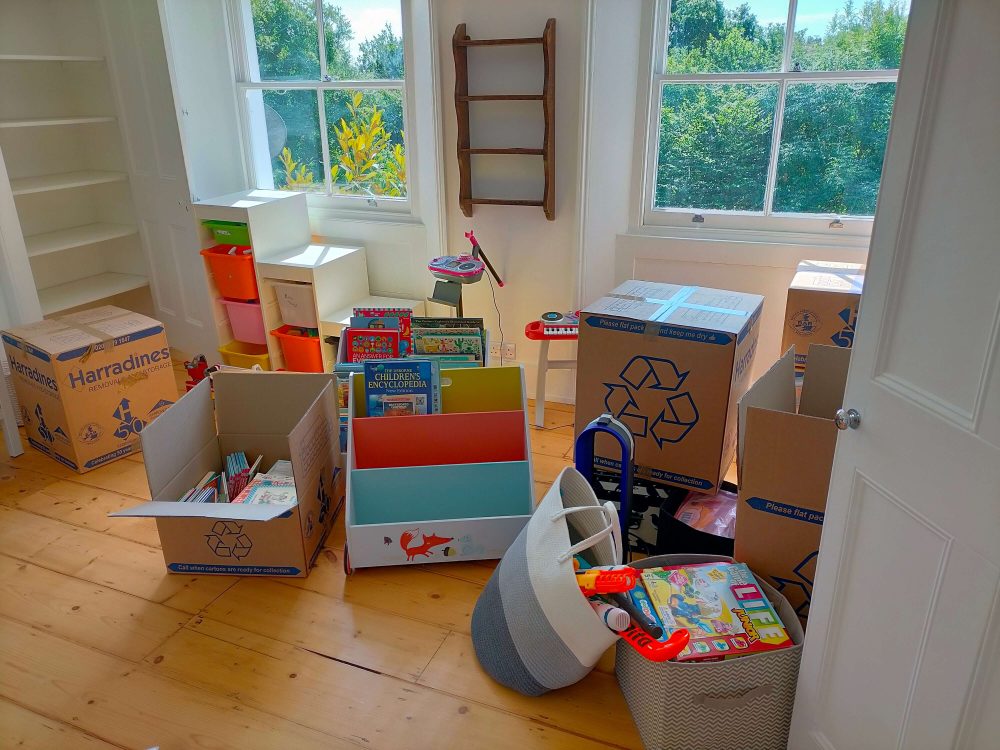 Post home staging picture showing a bright room filled with house moving boxes 